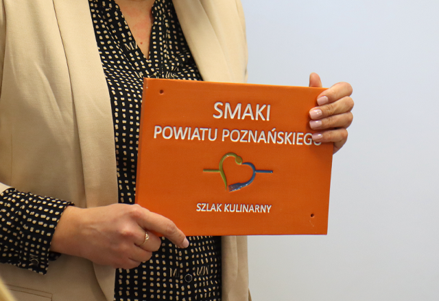 Smaki powiatu Poznańskiego Kobieta trzyma tabliczkę Smaki powiatu Poznańskiego